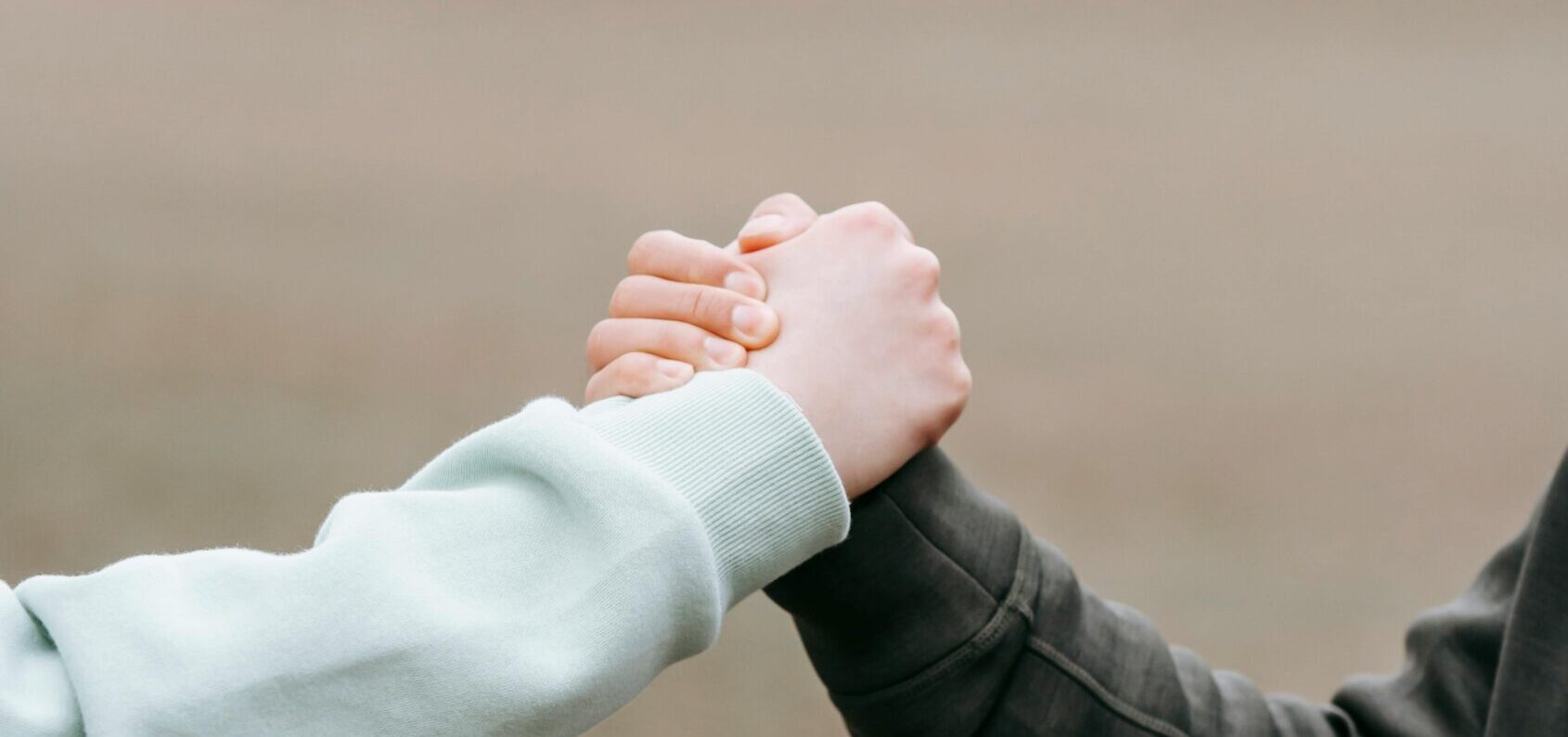 Two adults holding hands in an outdoor park setting, symbolizing trust and connection.